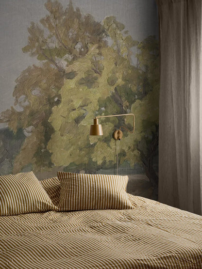 In the wallpaper Hedgerow Landscape’s open landscape, bushes and towering oaks emerge against a light grey-blue sky, as if on a large mural. 