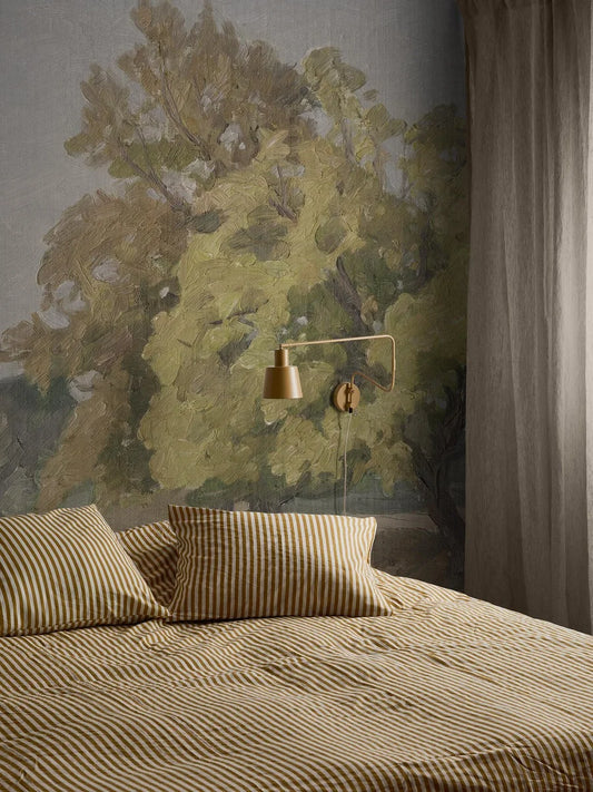 In the wallpaper Hedgerow Landscape’s open landscape, bushes and towering oaks emerge against a light grey-blue sky, as if on a large mural. 