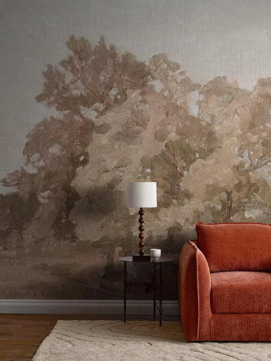 The Hedgerow Landscape mural wallpaper features a wide, open landscape with large, beautiful treetops silhouetted against a warm grey sky. 