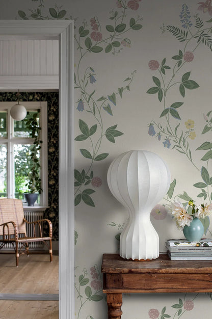 Floral Midsummer Eve Grand climbs toward the ceiling like a summery, delicate wall painting with buttercups, columbines, bellflowers, clover, and other blossoms in a light pastel palette on a cream-white background.