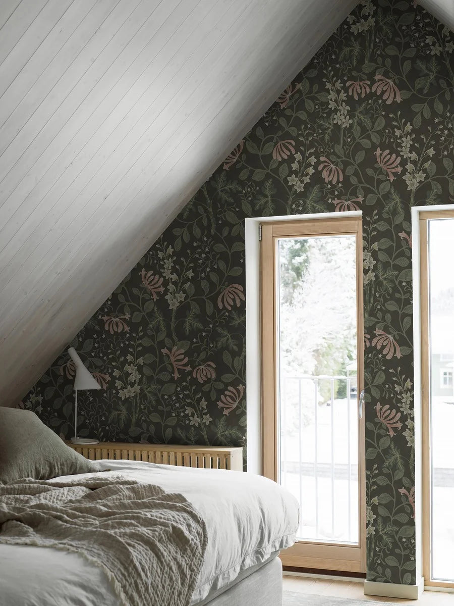 The Trädgårdsfröjd Grand mural wallpaper is covered in cream-coloured delphiniums and pale apricot-pink honeysuckle set within green, winding foliage on a dark green background