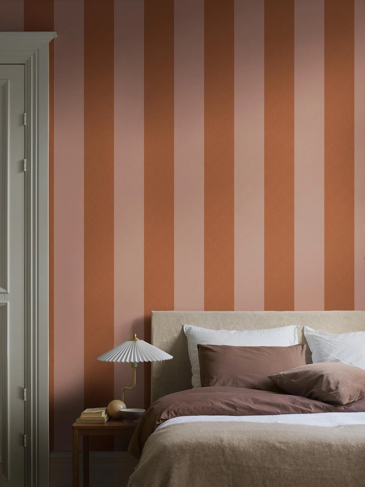 Bjärö Stripe is a boldly wide-striped wallpaper that makes no apologies. Here, the generously sized block stripes are rendered in light peach–apricot and muted orange.