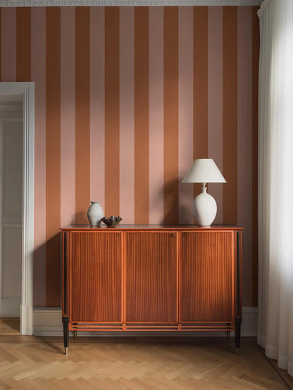 Bjärö Stripe is a boldly wide-striped wallpaper that makes no apologies. Here, the generously sized block stripes are rendered in light peach–apricot and muted orange.