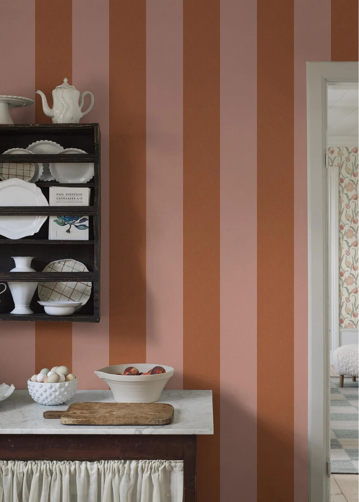Bjärö Stripe is a boldly wide-striped wallpaper that makes no apologies. Here, the generously sized block stripes are rendered in light peach–apricot and muted orange.