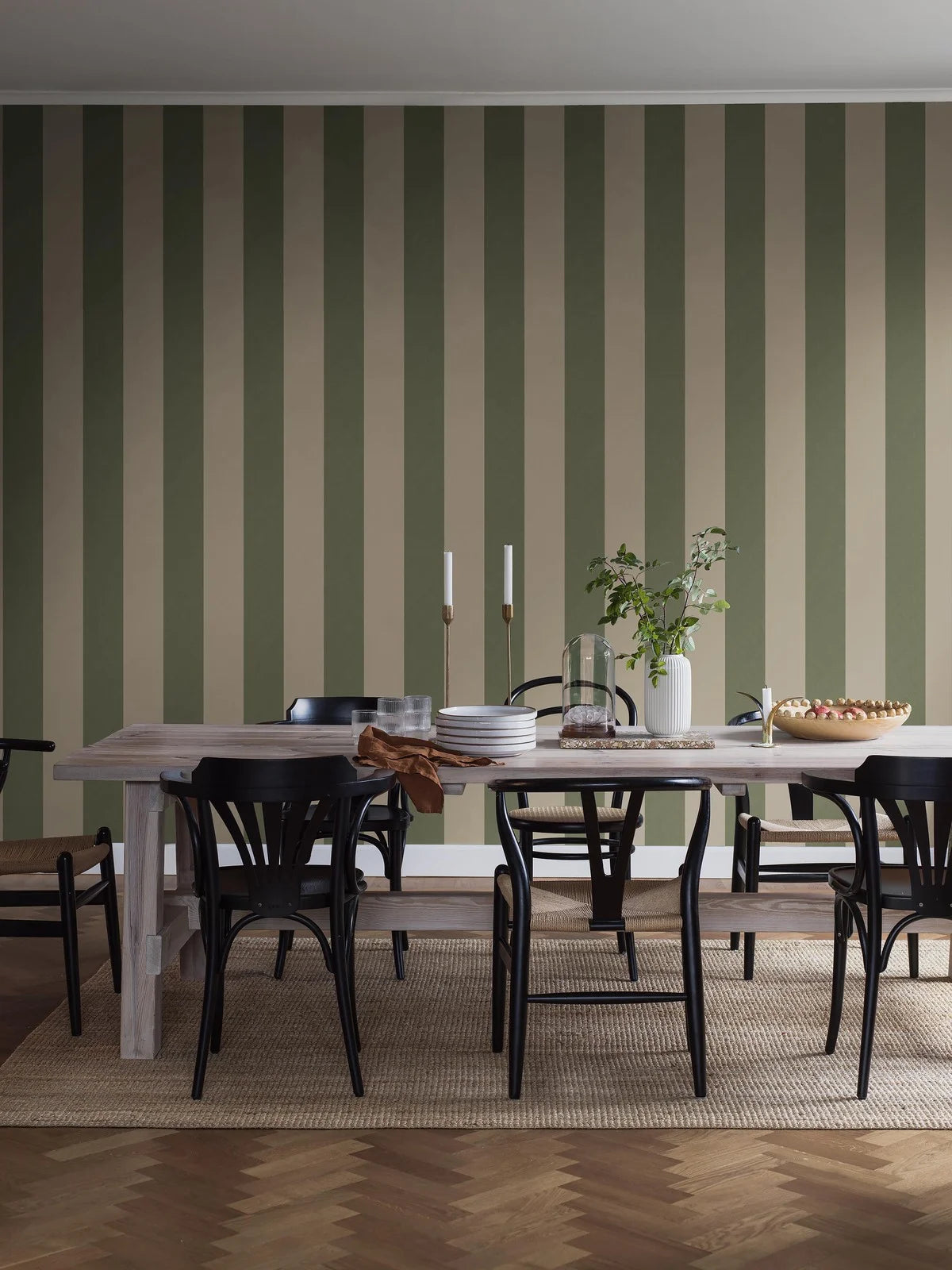 Bjärö Stripe is a striped wallpaper with generously wide block stripes – a graphic pattern that feels calm while still creating a clear focal point in the room.
Here, the wide-striped Bjärö Stripe wallpaper appears in a soft, harmonious color combination of antique green and putty white