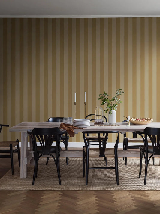 Båstad Stripe is a classic wide-striped wallpaper with softly contrasting block stripes. Here, the rhythmic pattern is rendered in yellow tones with subtle depth, where deep sun yellow meets muted butter yellow.