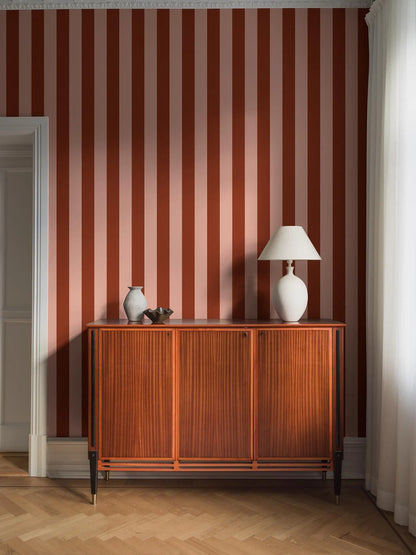 The wide-striped Båstad Stripe wallpaper feels warm and vibrant, with block stripes in raspberry red and warm light pink.