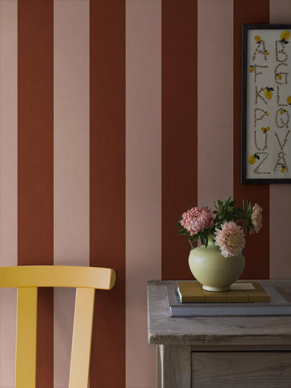 The wide-striped Båstad Stripe wallpaper feels warm and vibrant, with block stripes in raspberry red and warm light pink.