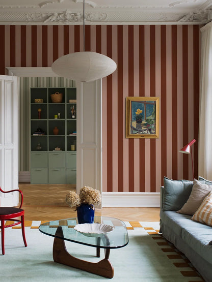 The wide-striped Båstad Stripe wallpaper feels warm and vibrant, with block stripes in raspberry red and warm light pink.