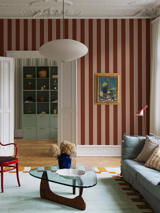 The wide-striped Båstad Stripe wallpaper feels warm and vibrant, with block stripes in raspberry red and warm light pink.