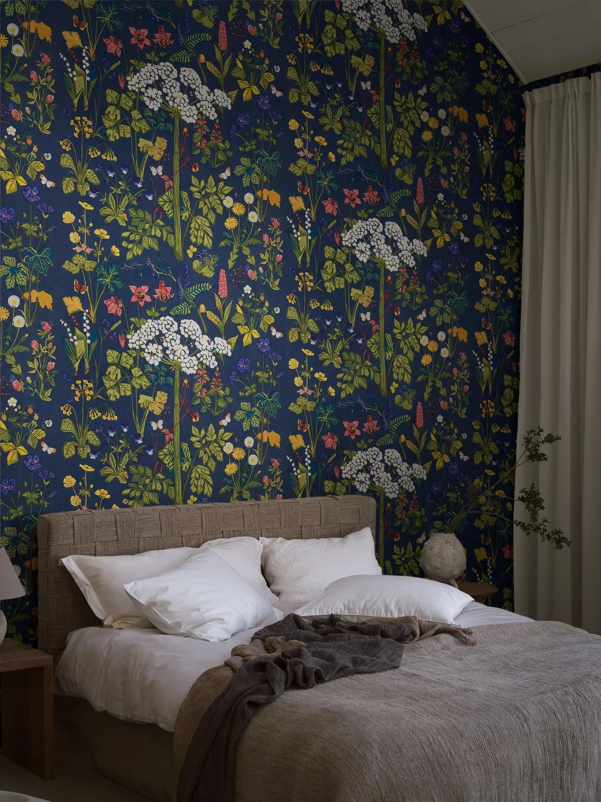 The mural wallpaper Aurora features one of Lisbet Jobs’ most beloved patterns, with flowers such as hogweed, dandelion, cowslip and lily of the valley, here in bright colors on a deep blue ground.