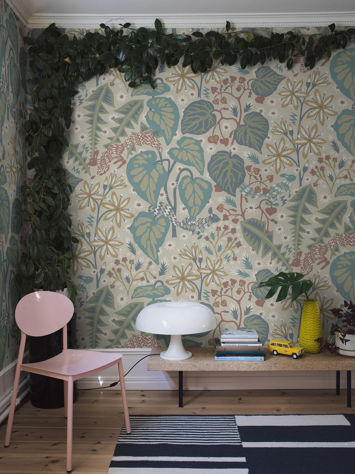 In the large-scale botanical pattern of the mural wallpaper Zingkorre, squirrels dart back and forth among flowers and leaves.