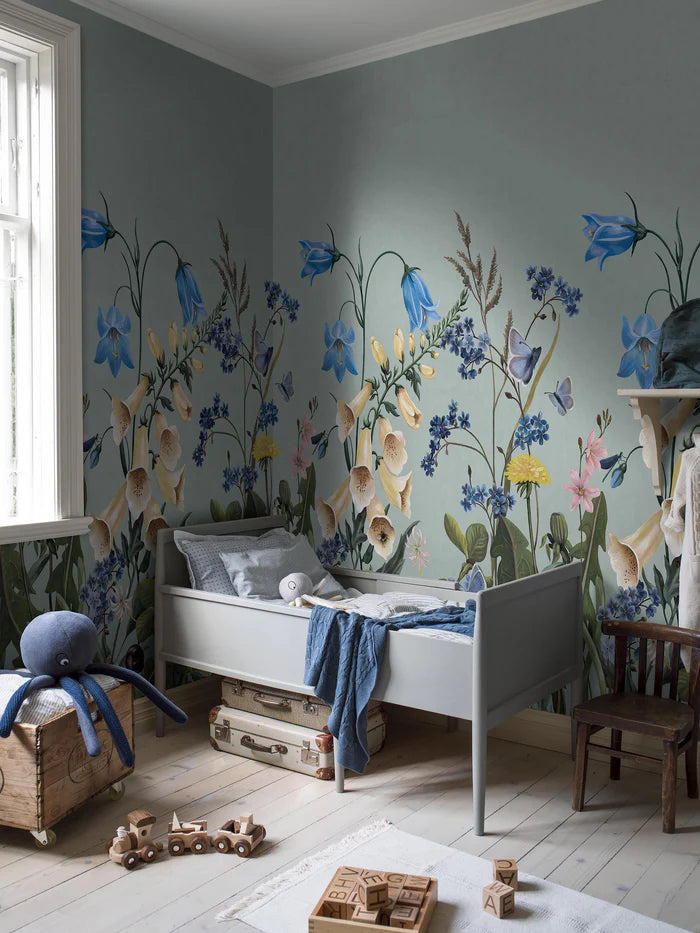 On the Bluebell Magic mural wallpaper, meadow flowers — bluebells, clover, dandelions, and forget-me-nots — stretch gracefully toward the ceiling