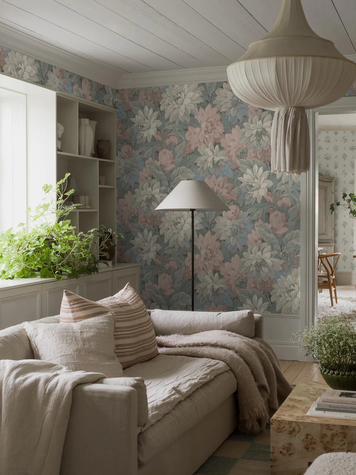 Here, Delilah Grand Wallpaper murals lush dahlia design appears in a soft pastel palette: flowers in muted shades of pink, blue, grey and white set against light blue-green foliage.