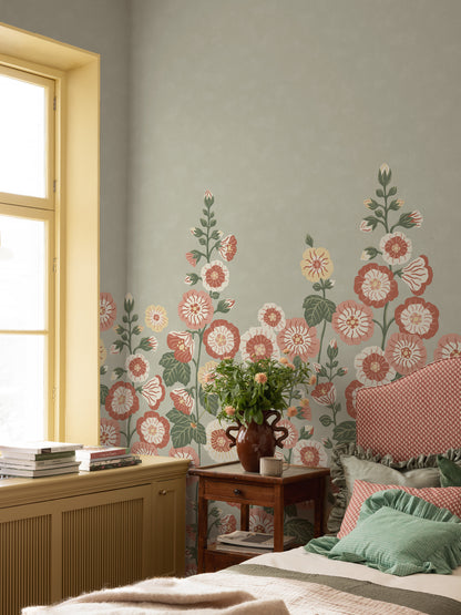 Happy Hollyhocks Grand is a vibrant floral wallpaper where lush hollyhocks grow all the way up to the ceiling.