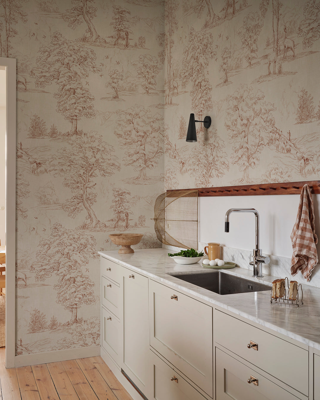Follow the beautiful hiking trails on the edge of the Pyrenees mountains among flocks of sheep and wild deer. This toile wallpaper is Sandberg's own travelogue from Southern France with a hand-drawn illustration on a becoming textile background, in a warm terracotta hue.