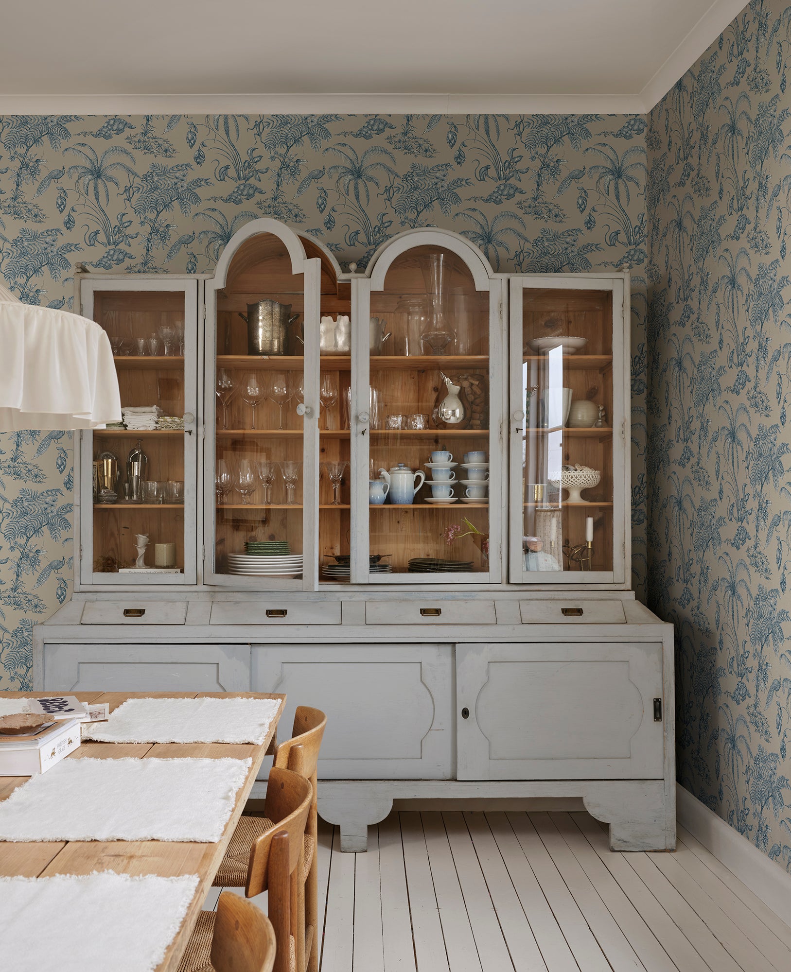 Moa, Indigo Blue wallpaper features a soft beige background with intricate botanical illustrations in indigo blue.