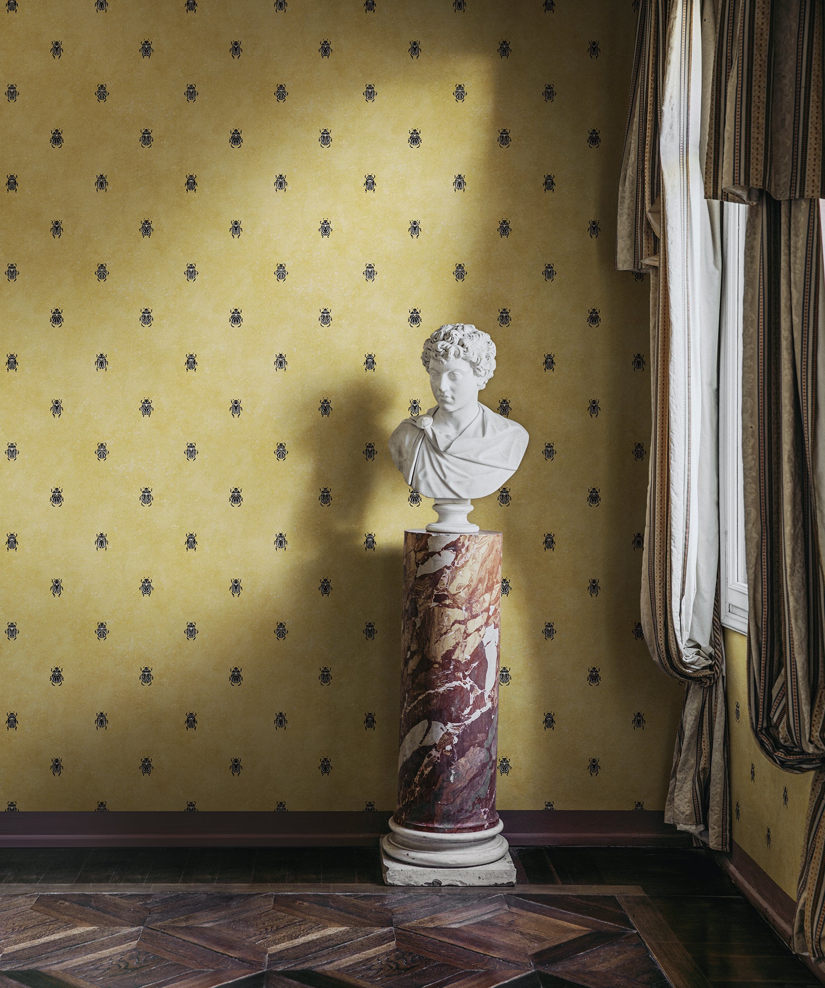 Wallpaper with stylized scarabs with decorative detailing in a row against a patinated background create a bold and chic atmosphere on the walls.