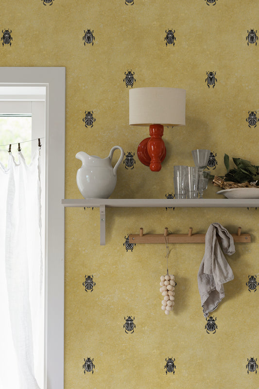 Wallpaper with stylized scarabs with decorative detailing in a row against a patinated background create a bold and chic atmosphere on the walls.