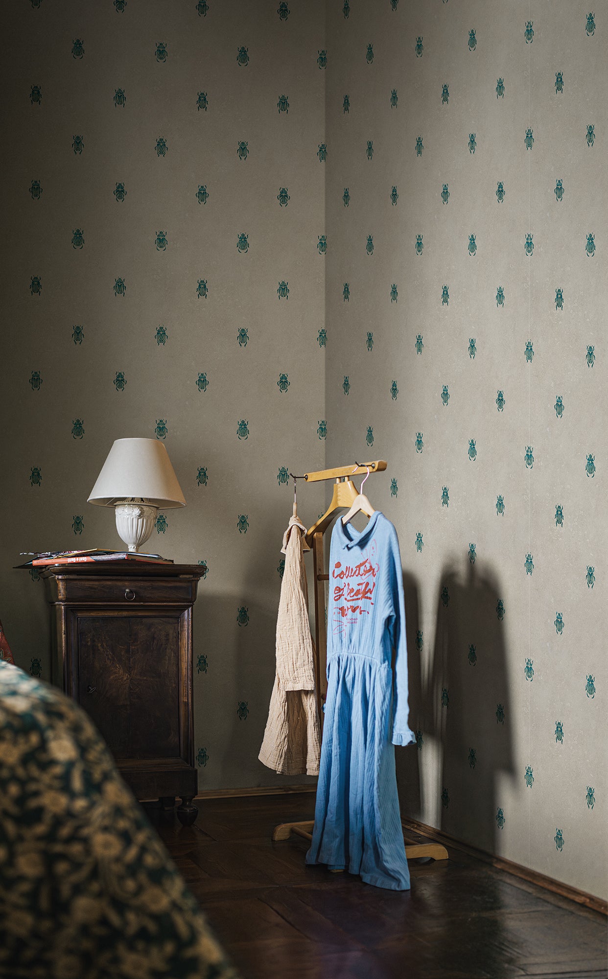 Wallpaper with stylized scarabs with decorative detailing in a row against a patinated background create a bold and chic atmosphere on the walls.