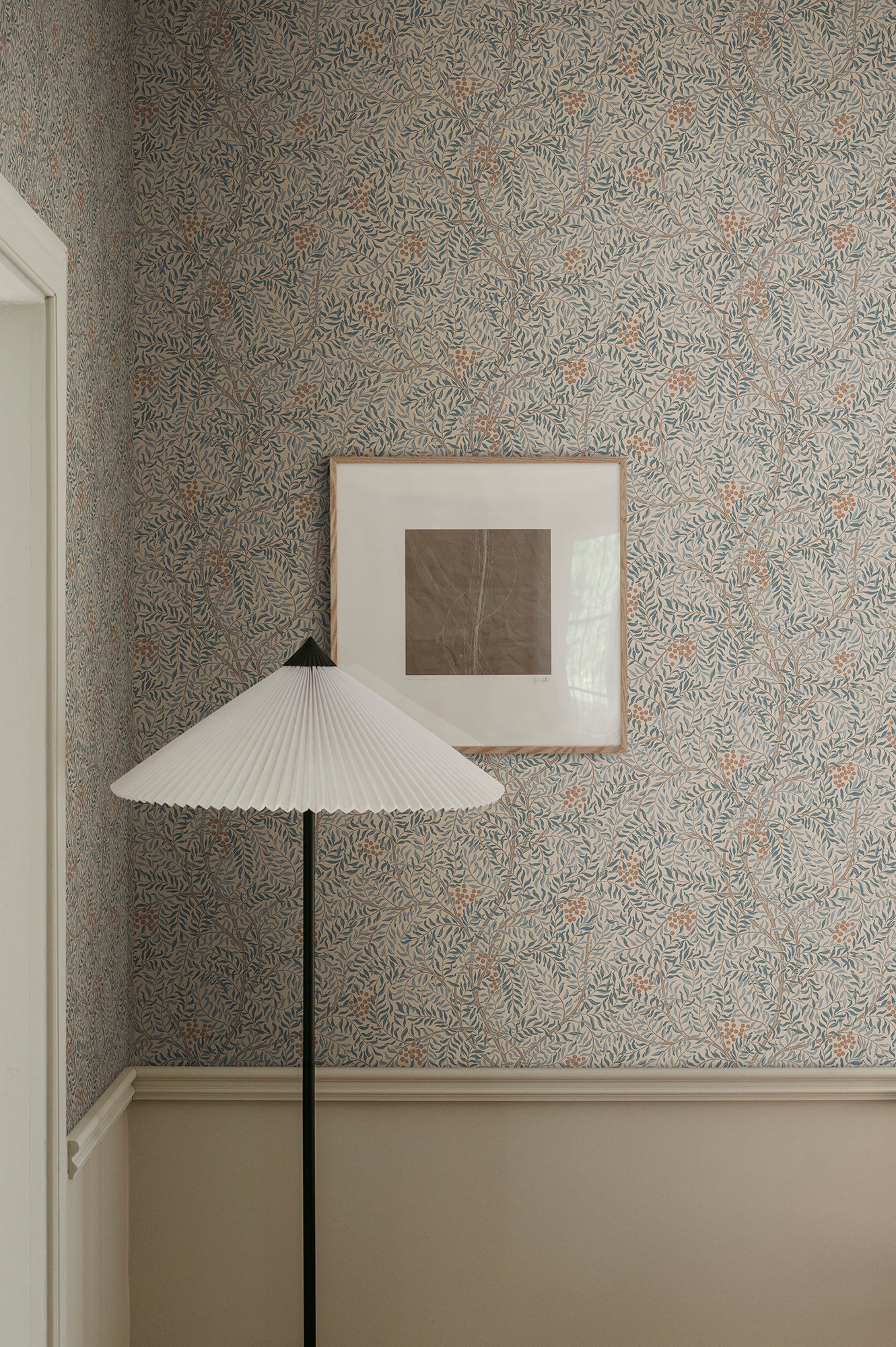 A harmonious surface-printed wallpaper pattern featuring intricate rowan berry branches creates a cozy and welcoming atmosphere with its stylized and enveloping design.