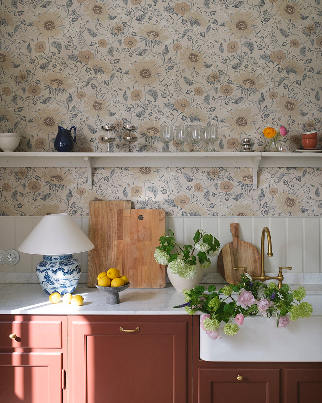 Wallpaper Solveig, Misty Blue, has a warm beige base adorned by flowers in warm beige and white, with misty blue foliage.