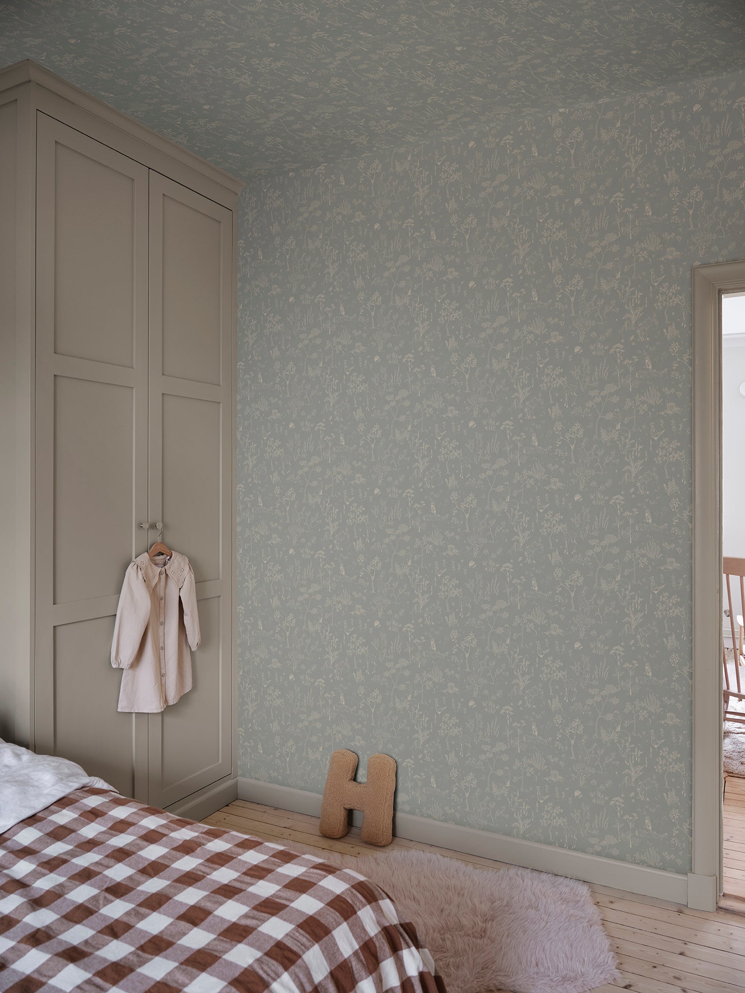 Discover the Hollie wallpaper, where a misty blue backdrop unfolds a fantasy forest teeming with whimsical animals and delicate botanical details.