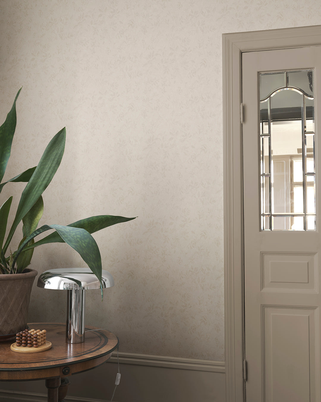 Infuse your space with the elegance of the Mila Beige wallpaper. This pattern, inspired by antique al fresco paintings, features romantic leafy vines with a warm patina. The subtle depth and aged aesthetic seamlessly blend into any room, bringing a touch of timeless sophistication.