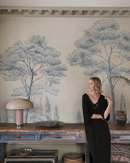 Enhance your space with the Andrea mural's classical charm. Featuring hand-drawn Italian gardens in serene blue, this piece infuses any room with historical and natural beauty. Tall conifers stand majestically, creating a sense of depth and timeless elegance that transforms your walls into a picturesque landscape.
Designed by Karolina Kroon