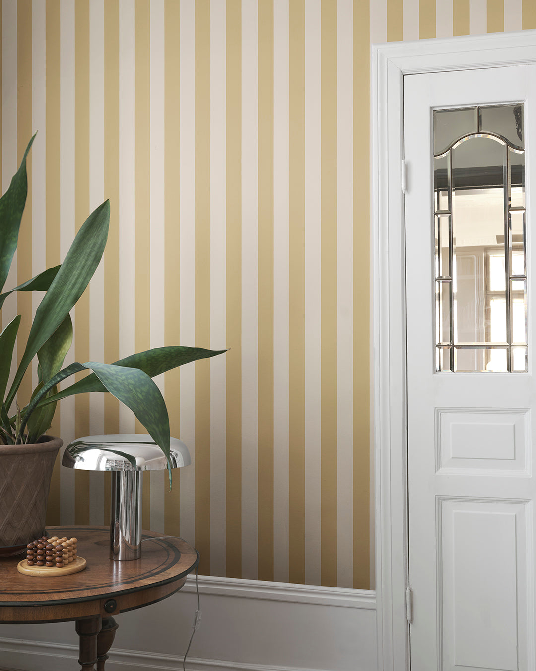 The Sam, Honey wallpaper features timeless stripes in warm hues, adding a touch of Southern European elegance to any room. Ideal for those seeking a blend of classic and contemporary style in their space.