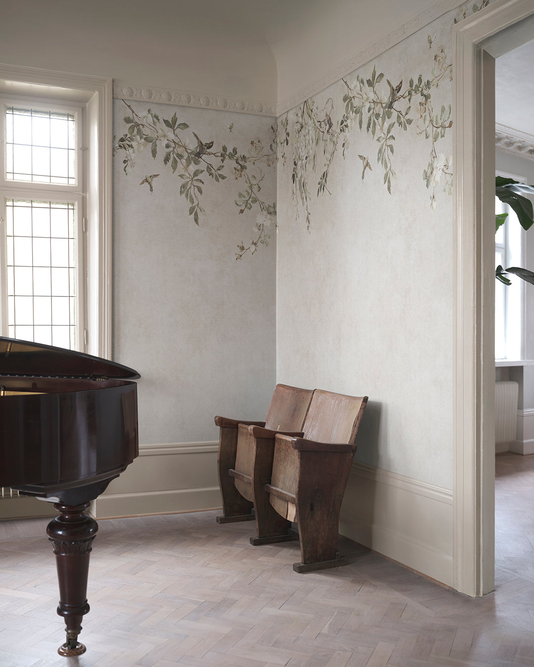 Transform your space with the Nico mural. This design evokes a serene Mediterranean pergola, featuring delicate blooming vines and small birds against a soft, lime-washed backdrop. 