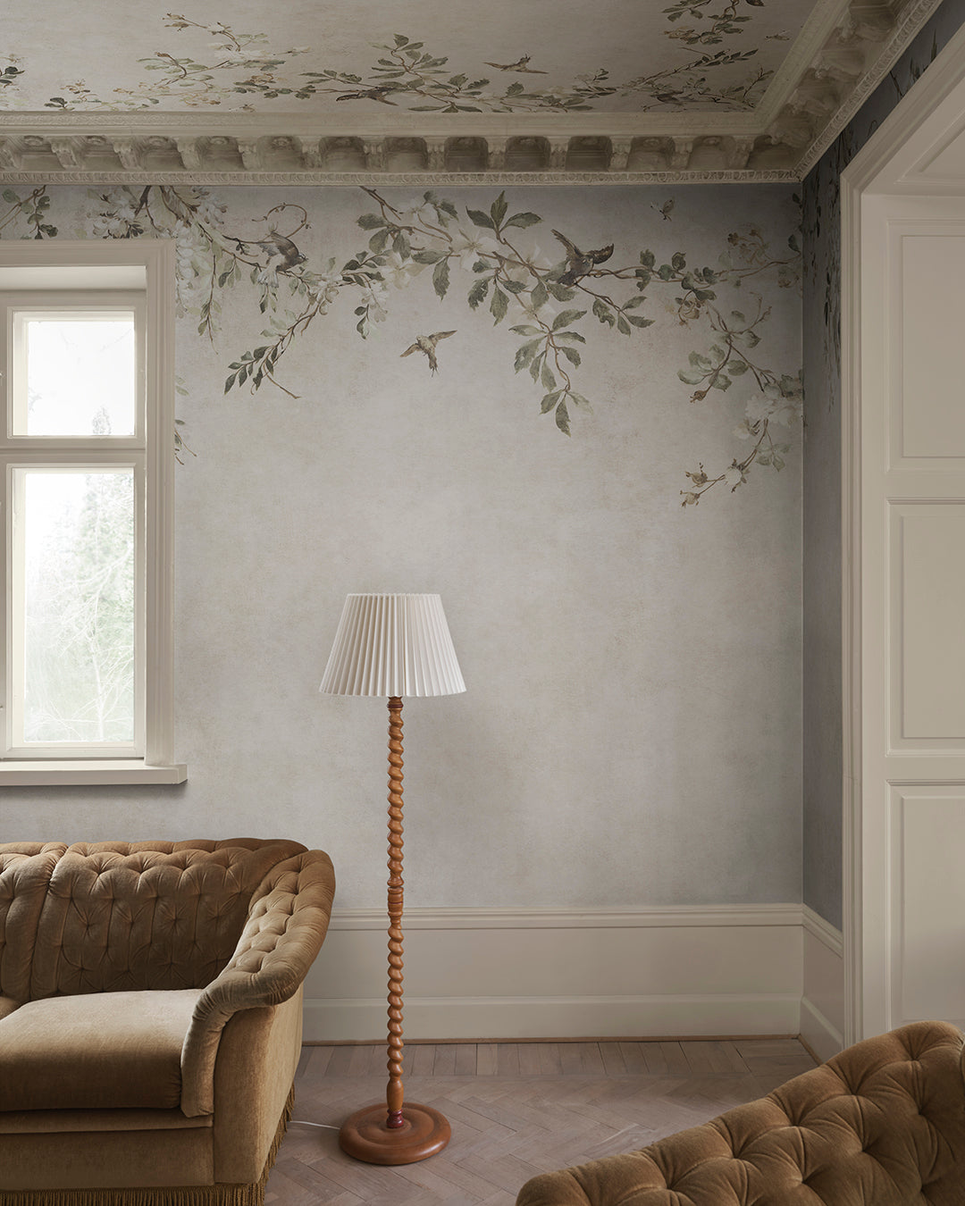 Transform your space with the Nico mural. This design evokes a serene Mediterranean pergola, featuring delicate blooming vines and small birds against a soft, lime-washed backdrop. 