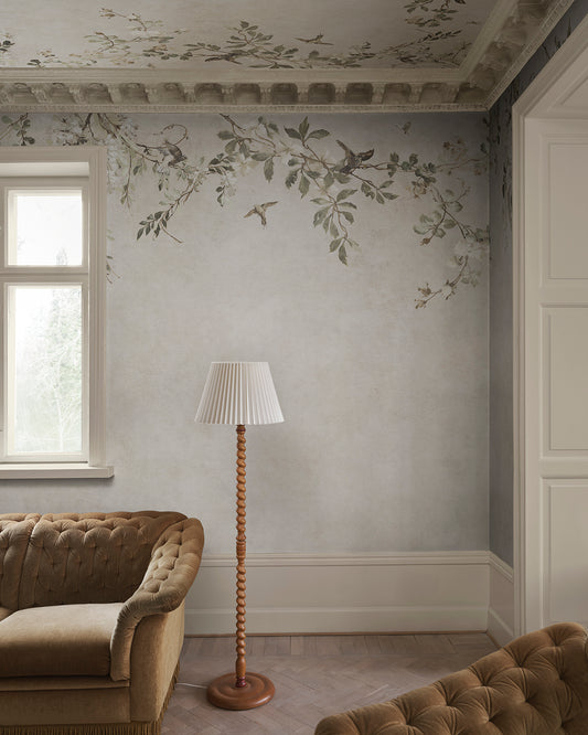 Transform your space with the Nico mural. This design evokes a serene Mediterranean pergola, featuring delicate blooming vines and small birds against a soft, lime-washed backdrop. 
